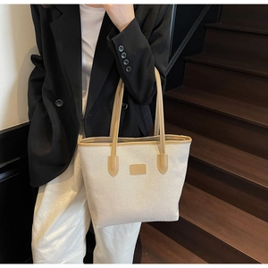 Detail of canvas tote bag with brown leather trim shown on dark wooden stairs