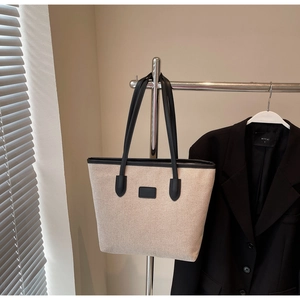 Detail of off-white canvas tote bag with black leather straps and top trim for work