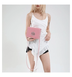 Close-up of pink crossbody bag featuring woven texture and silver M logo detail