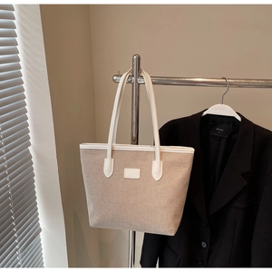 Detail of canvas tote bag with white leather handles and reinforced edges for durability