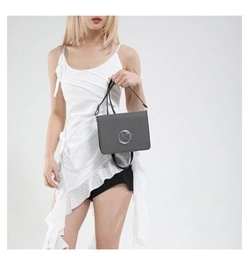 Detail of dark grey crossbody bag with silver M logo buckle and fine pebble texture