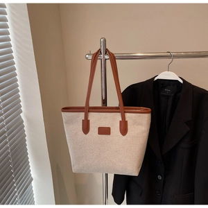 Detail of canvas tote bag with brown faux leather trim and sturdy shoulder handles