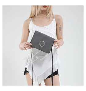 Detail of dark grey crossbody bag with silver M logo and thin shoulder strap