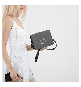 Close-up of a vintage grey textured crossbody bag with a metallic M logo buckle detail