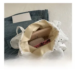 Dettaglio della borsa tote bianca a fiori che mostra la grande capacità per libri e oggetti