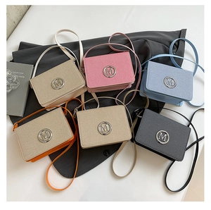 Flat lay of small square camera bags in six colors with silver M metal buckles and straps