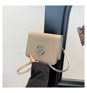Detail of khaki woven crossbody bag with silver M logo buckle and thin leather strap
