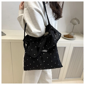 Detail of black floral mesh tote bag featuring a large bow shoulder strap and pleated fabric