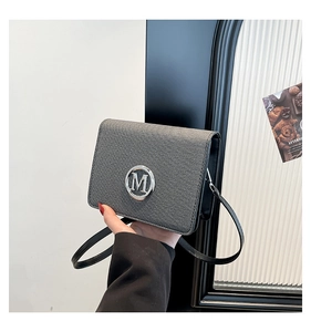 Detail of grey woven shoulder bag with silver M letter logo and elegant flap closure
