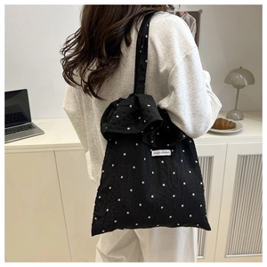 Detail of black floral mesh tote bag with ruffle trim and Magic Pocket woven label