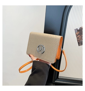 Close-up of woven flap texture and orange leather details with silver metal M logo