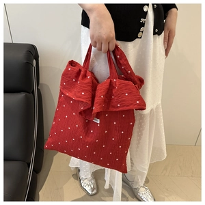 Detail of red floral tote bag featuring elegant ruffle edges and small flower patterns
