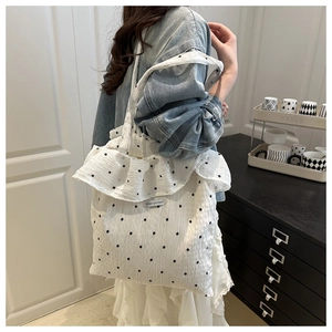 Detail of white mesh shoulder bag with black floral pattern and large ruffle trim