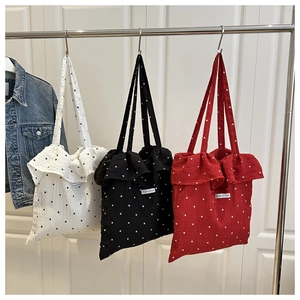 Detail of ruffled mesh tote bags with floral patterns and brand labels on hangers