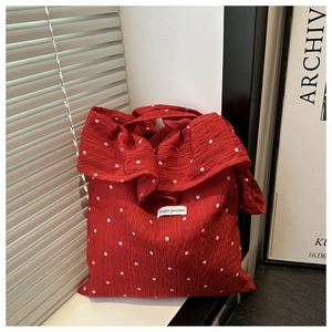 Detail of red mesh tote bag with white flower prints and Magic pocket label texture