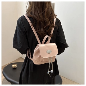 Detail of pink mini backpack featuring glossy texture and silver oval metal hardware