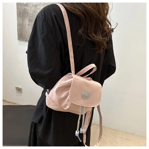 Detail of pink satin mini backpack with drawstring closure and fashion metal emblem