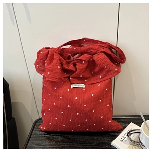 Detail of red floral mesh tote bag with large bow and Magic Pocket brand label