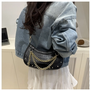 Model wearing a black crocodile embossed baguette bag with gold chain and rivet details