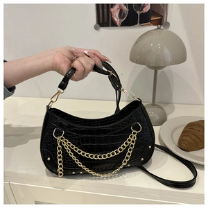 Detail of black crocodile texture crescent bag with triple gold chain decorative accents