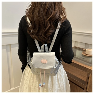 Detail of silver metallic mini backpack with pink drawstring and fashion logo label