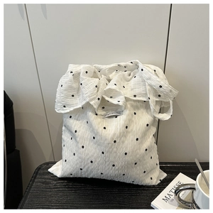 Close-up of seersucker texture with floral embroidery on white mesh shoulder bag