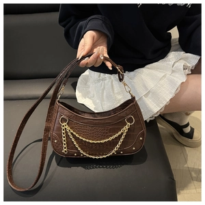Detail of brown crocodile pattern underarm bag with gold double chain and moon shape