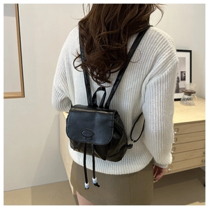 Detail of black faux leather backpack with drawstring closure and bead accents