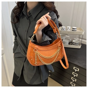 Detail showing orange crocodile pattern leather texture and gold chain on the bag