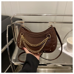 Detail of crocodile embossed dark brown hobo bag with luxury gold chain and stud accents
