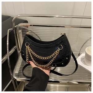 Detail of black croc-embossed half-moon bag with double gold chains and vintage rivets
