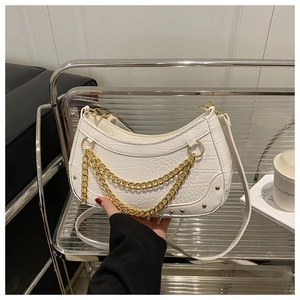 Close-up of white crocodile embossed half-moon bag with decorative gold chain straps