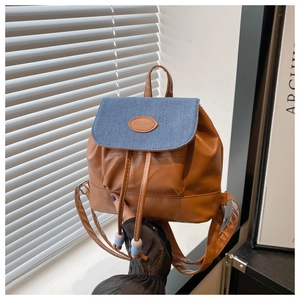 Close-up of brown faux leather and blue denim backpack with drawstring and beads
