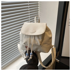 Detailed view of white mini backpack with fashion lettering and beaded drawstring details