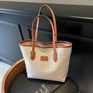 Minimalist cream canvas tote bag with brown leather trim and large storage capacity
