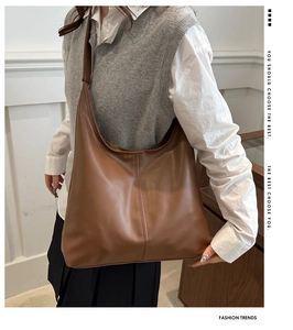 Detail shot of a brown vintage leather tote bag showing fine texture and vertical stitching