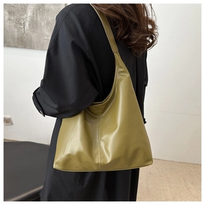 Back view of a large olive green PU leather tote bag worn by a model in a minimalist room