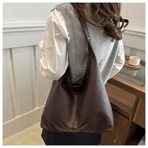 Detailed view of flexible dark brown PU leather tote bag worn as a shoulder bag