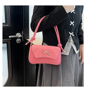 Détail du sac baguette rose avec boucle dorée et design de bandoulière nouée élégante