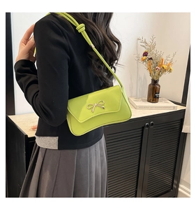 Détail du sac sous le bras vert fluo avec fermoir nœud doré et bandoulière nouée