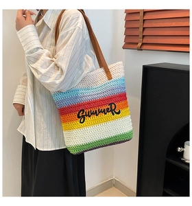 Detail of rainbow striped woven bucket bag featuring black Summer embroidery and leather strap