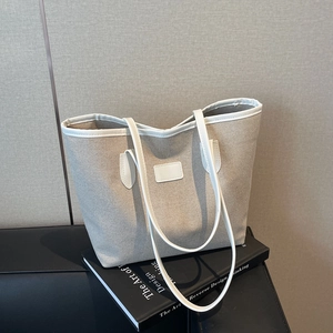 Minimalist beige canvas tote bag with white faux leather trim for chic office commuting