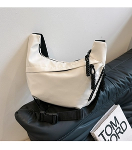 Detailed view of modern white asymmetrical sling bag with black ropes and buckle closure