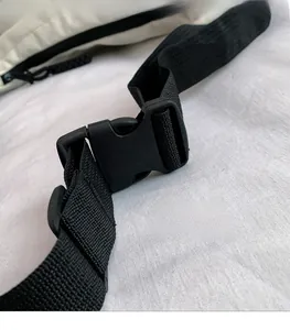 Detail of adjustable black nylon strap with durable plastic buckle on beige tote bag