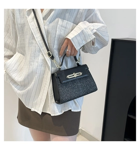 Detail shot of a black sequin crossbody bag styled with a white striped shirt and brown skirt