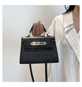 Detailed view of black Kelly bag with sparkling crystals and golden metal twist-lock