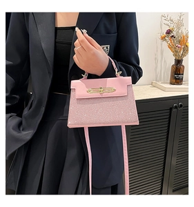 Detailed view of pink Kelly-style bag featuring glitter fabric and golden metal buckle