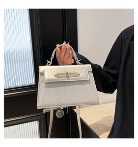 Detail of silver sequined handbag featuring metal turn-lock closure and leather top handle
