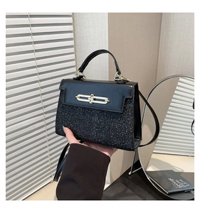 Detail of elegant black bag featuring a sparkling glitter texture and golden metal twist lock