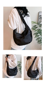 Macro view of large black crescent tote bag featuring a decorative woven rope zipper pull